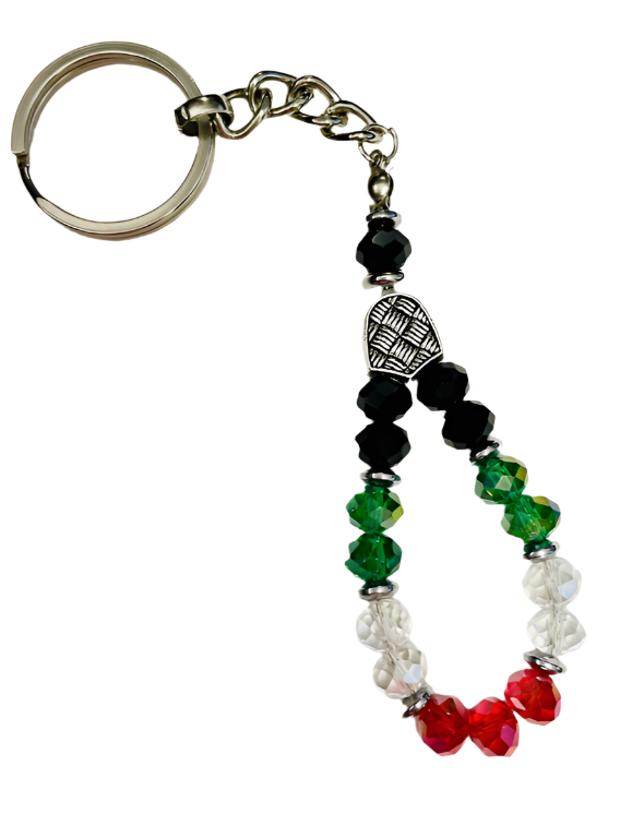 Add a touch of national elegance to your keys with this attractive handmade keychain crafted from shimmering crystal beads. The four colors of the Palestinian flag – black, green, white, and red – come together in a harmonious design that embodies the spirit of steadfastness and pride. Each crystal bead is carefully polished to reflect light and add a distinctive sparkle, interspersed with elegant silver metallic spacers that enhance its beauty. The keychain is topped with a decorative metallic piece adorne