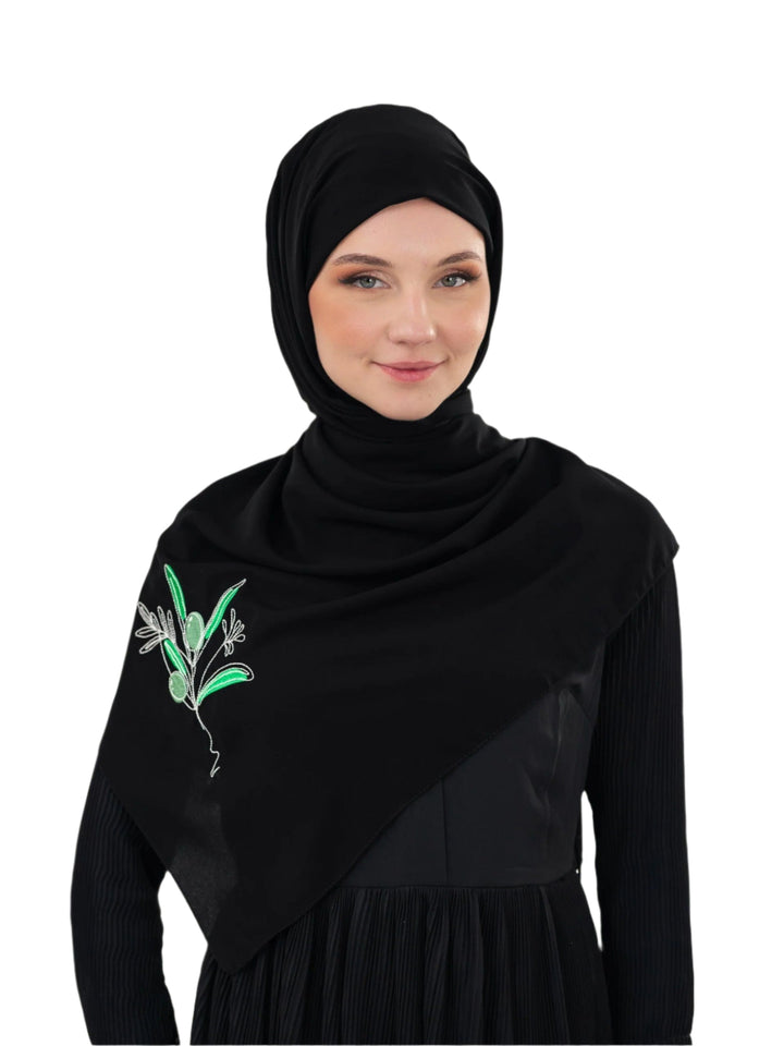 Discover expressive elegance with this luxurious black scarf, meticulously crafted from high-quality polyester that offers a soft touch and perfect drape. Measuring 70 x 180 cm, the scarf is versatile for various styling preferences. It is adorned with exquisite and detailed embroidery of a vibrant green olive branch, which is not merely an embellishment, but a profound symbol of peace, resilience, and a deep connection to the land and the rich Palestinian identity. Wear this scarf to express your refined t