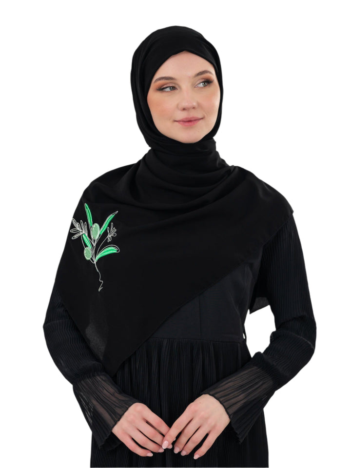 Discover expressive elegance with this luxurious black scarf, meticulously crafted from high-quality polyester that offers a soft touch and perfect drape. Measuring 70 x 180 cm, the scarf is versatile for various styling preferences. It is adorned with exquisite and detailed embroidery of a vibrant green olive branch, which is not merely an embellishment, but a profound symbol of peace, resilience, and a deep connection to the land and the rich Palestinian identity. Wear this scarf to express your refined t