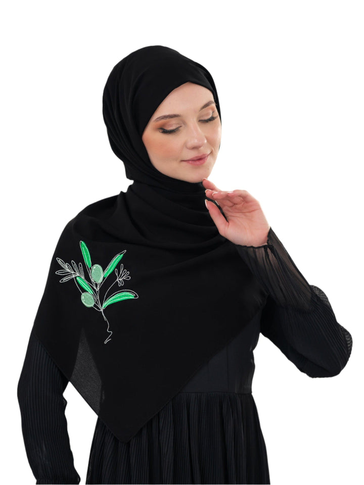 Discover expressive elegance with this luxurious black scarf, meticulously crafted from high-quality polyester that offers a soft touch and perfect drape. Measuring 70 x 180 cm, the scarf is versatile for various styling preferences. It is adorned with exquisite and detailed embroidery of a vibrant green olive branch, which is not merely an embellishment, but a profound symbol of peace, resilience, and a deep connection to the land and the rich Palestinian identity. Wear this scarf to express your refined t