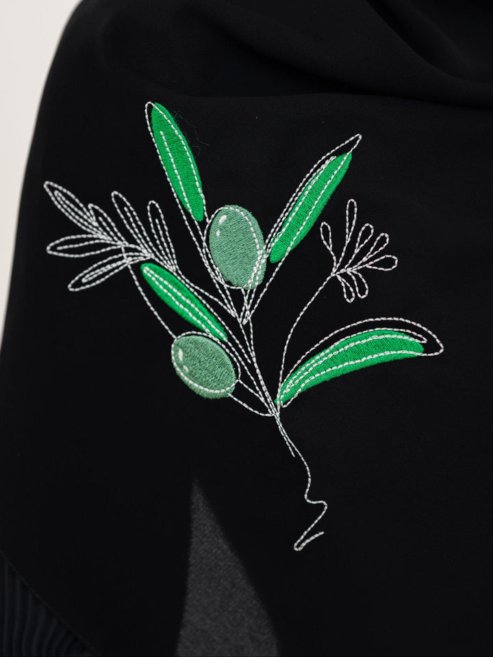 Discover expressive elegance with this luxurious black scarf, meticulously crafted from high-quality polyester that offers a soft touch and perfect drape. Measuring 70 x 180 cm, the scarf is versatile for various styling preferences. It is adorned with exquisite and detailed embroidery of a vibrant green olive branch, which is not merely an embellishment, but a profound symbol of peace, resilience, and a deep connection to the land and the rich Palestinian identity. Wear this scarf to express your refined t