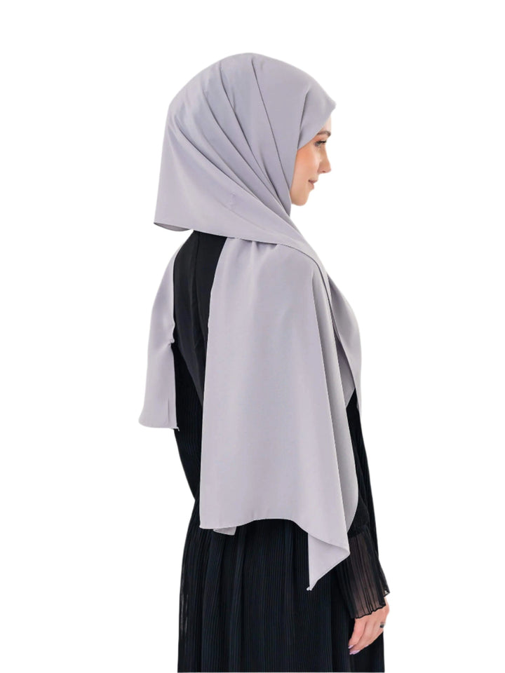 Woman wearing a light gray hijab on a white background
