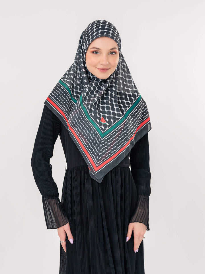 Woman wearing a black hijab with geometric pattern on a plain background
