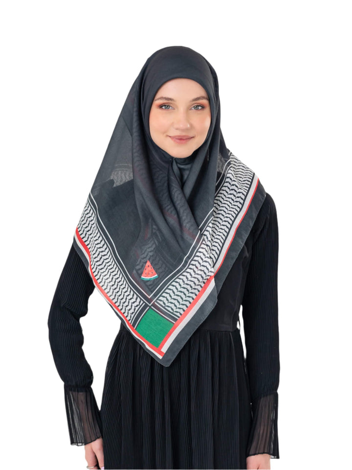 Woman wearing a black hijab with a patterned scarf draped over her shoulders on a white background
