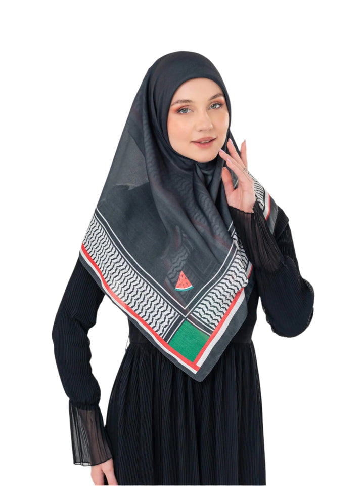 Woman wearing a black hijab with a colorful pattern, holding a phone to her ear on a white background