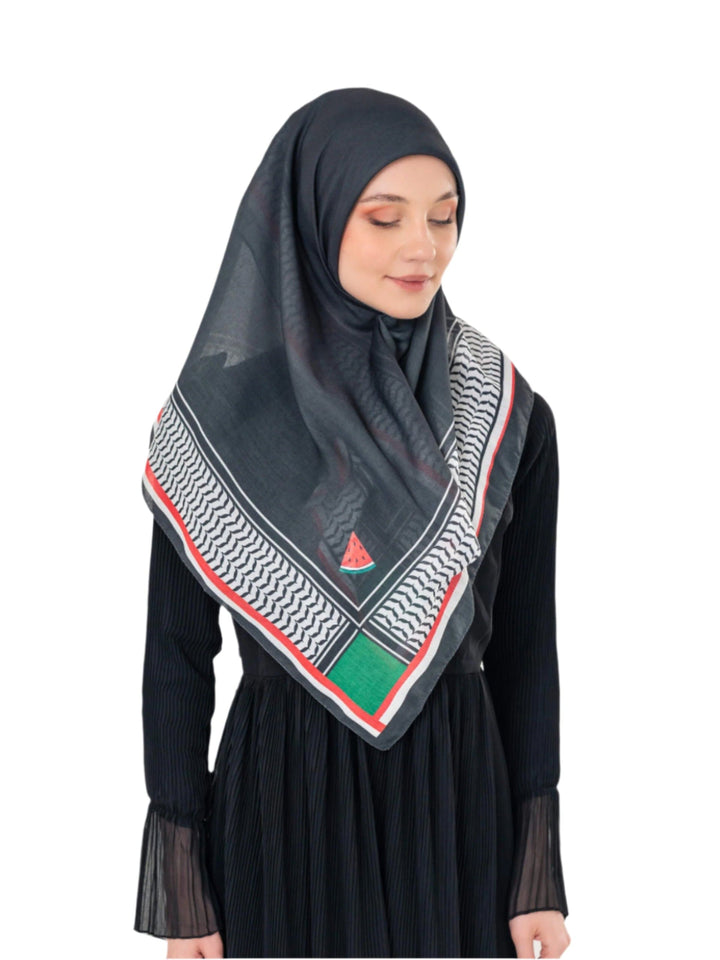 Woman wearing a black hijab with a patterned scarf on a white background