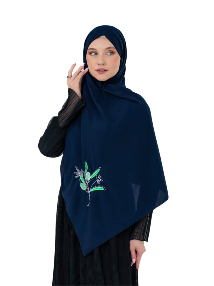 Woman wearing a dark blue hijab with floral embroidery on a white background