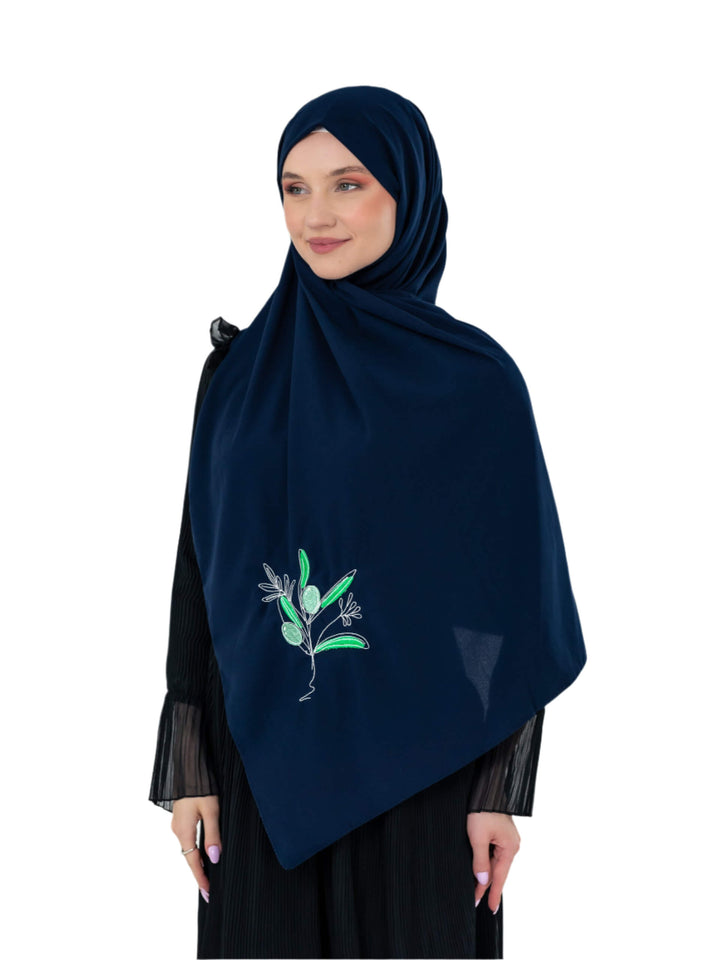 Woman wearing a navy hijab with floral embroidery on a white background