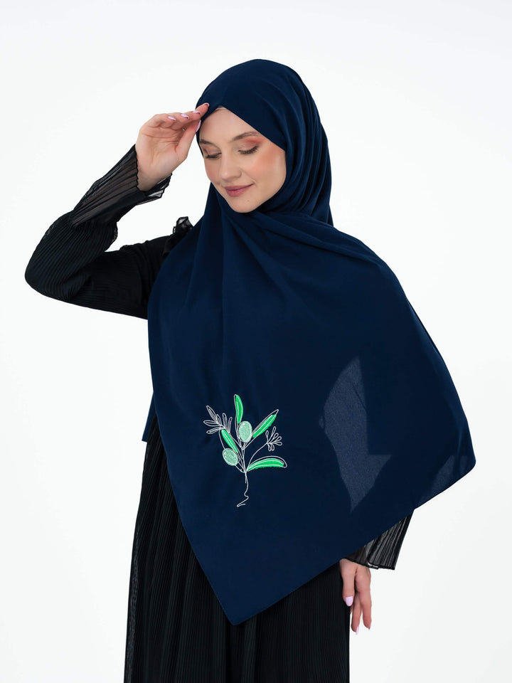 Woman wearing a navy hijab with a floral design on a white background