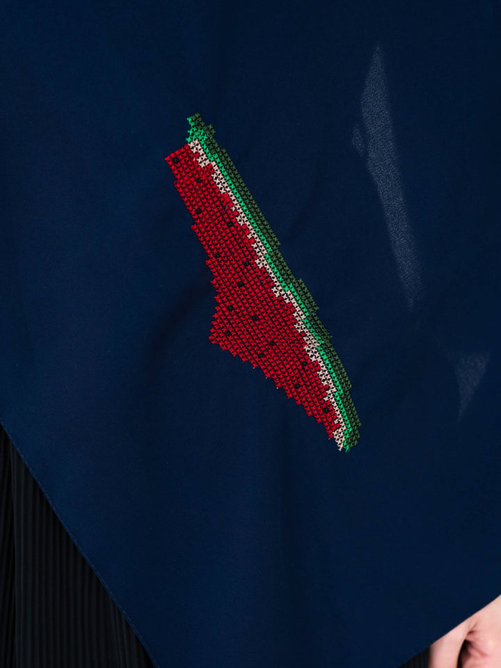Close-up of a red and green beaded design on a dark blue fabric.