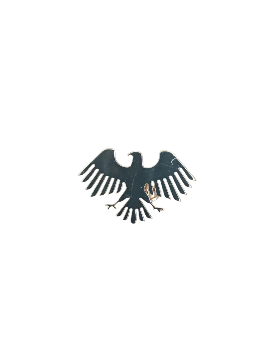 Metallic eagle emblem on a wooden surface with a pen and paper in the background.