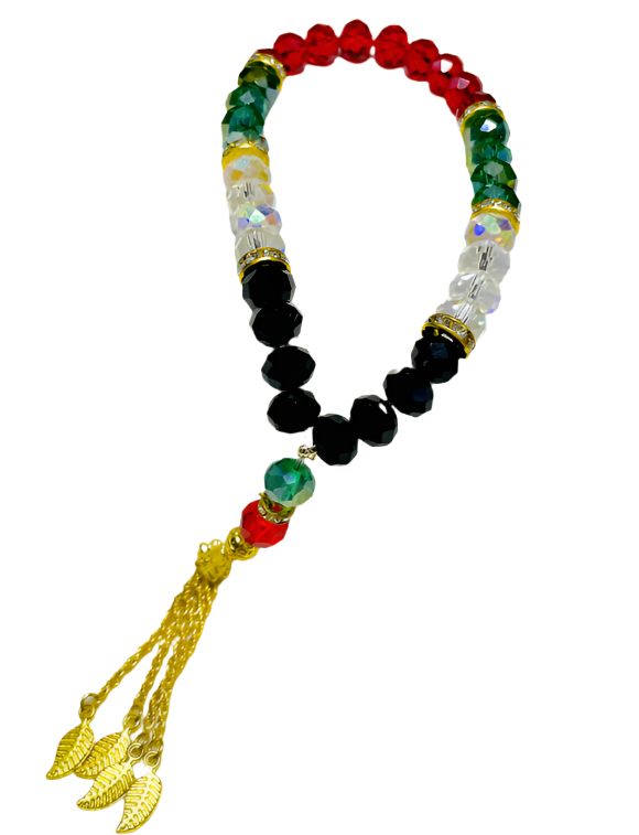 An elegant rosary featuring a design inspired by the colors of the Palestinian flag, where lustrous crystal beads in red, green, white, and black alternate, giving it a distinctive national character. Gold metallic spacers are interspersed between the beads, enhancing their sparkle and allure. The rosary is crowned with dangling golden metallic tassels, consisting of delicate chains ending with metallic leaf-shaped ornaments, adding a touch of luxury and sophistication to the rosary as a whole.
